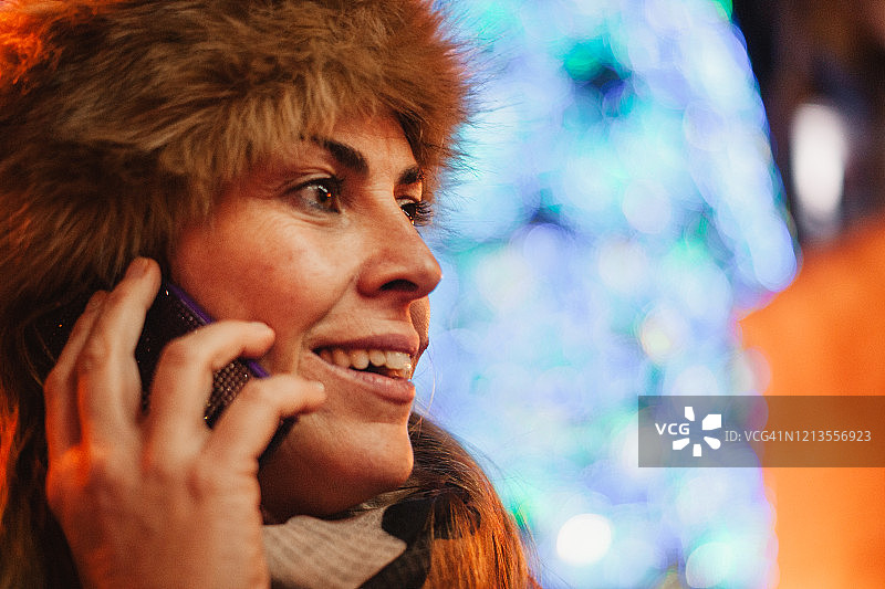 在马德里太阳门圣诞节用电话微笑交谈的成年女性图片素材