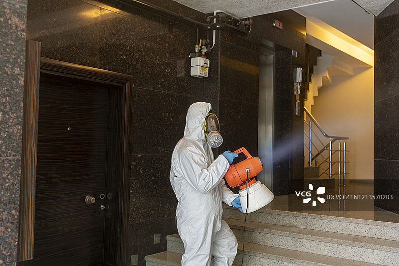 穿防护服的男人消毒公寓入口图片素材