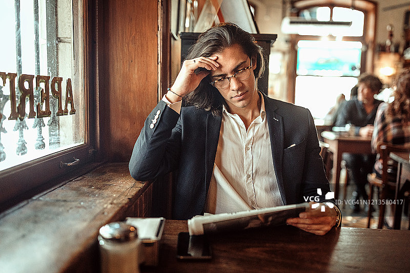 在当地咖啡馆阅读报纸的严肃商人图片素材