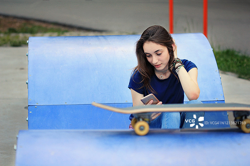 使用智能手机的漂亮滑板少女图片素材