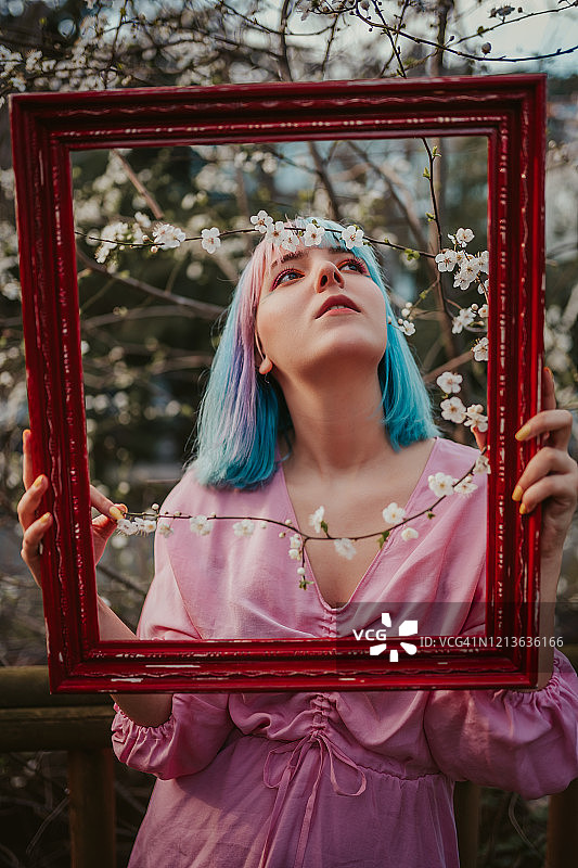 春天里拿着红色画框的蓝发女人图片素材