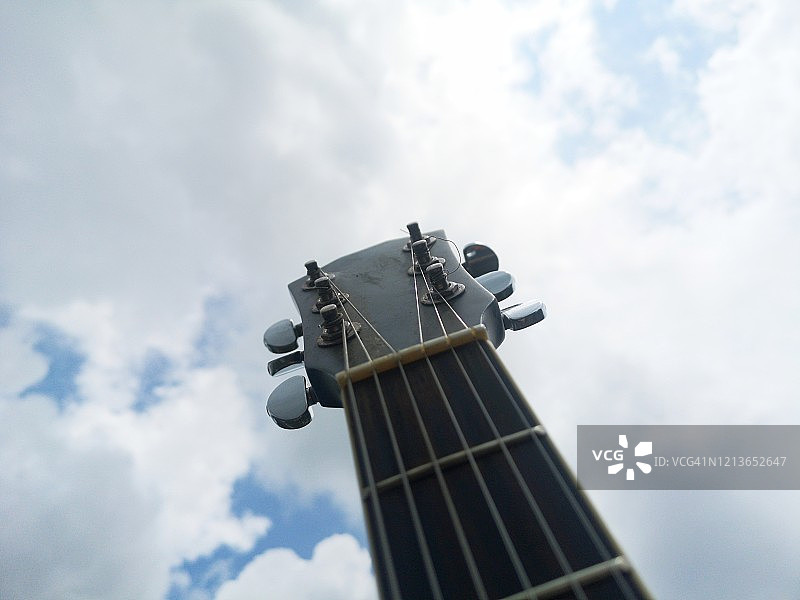 蓝色天空和云朵背景下的吉他琴头特写图片素材