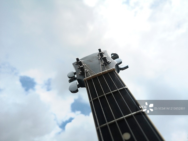 蓝色天空和云朵下的吉他琴头仰拍图片素材