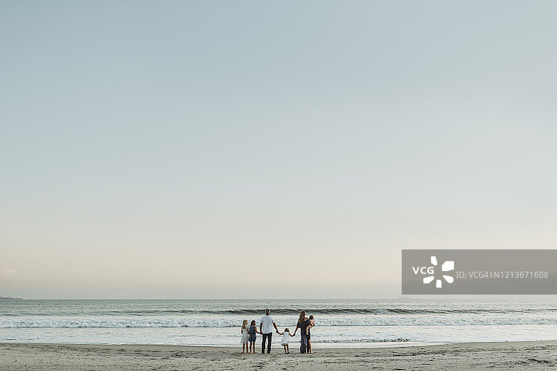 日落时分站在海边的年轻家庭图片素材