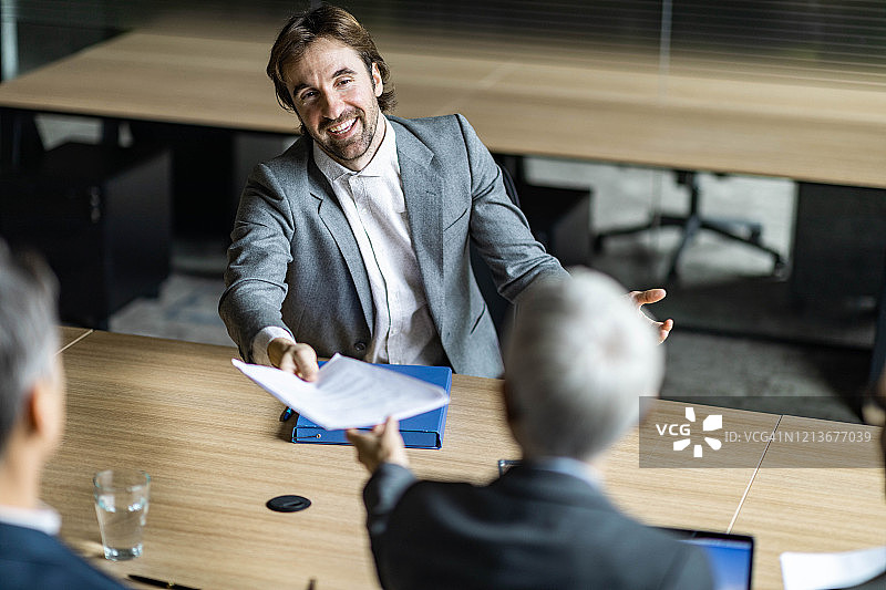 快乐的男候选人在面试中向人力资源团队递交简历图片素材