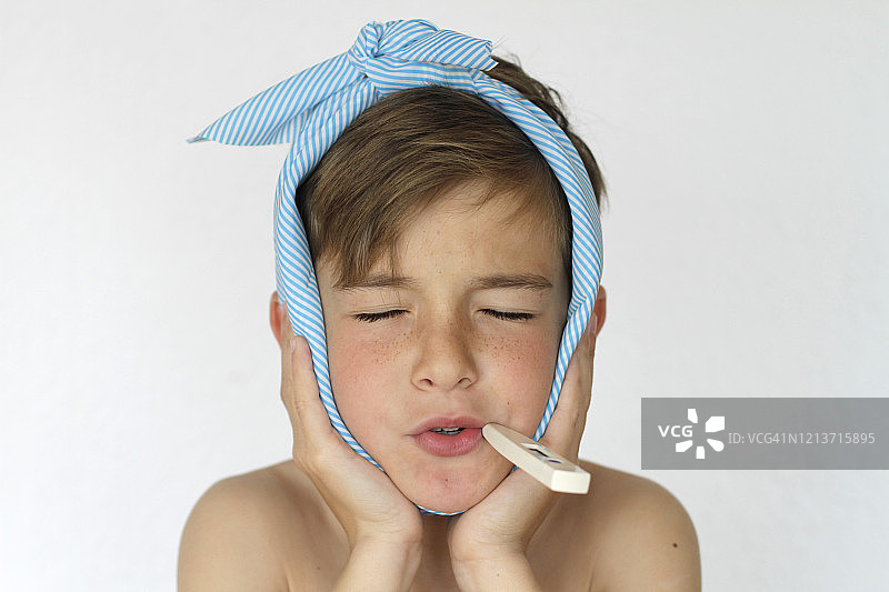 男孩头痛，嘴里含着体温计的肖像图片素材