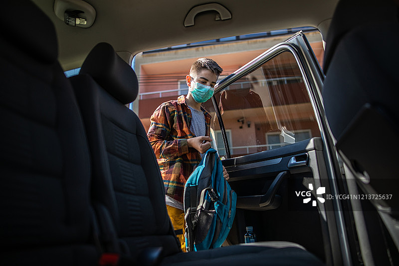 放学后戴着防护口罩进入汽车的青少年男孩图片素材