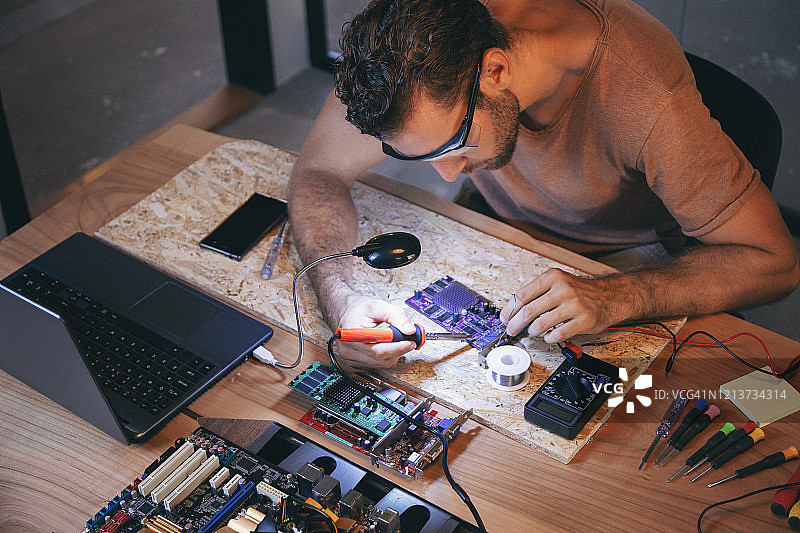 同事们在办公室里加班制作电路板。图片素材