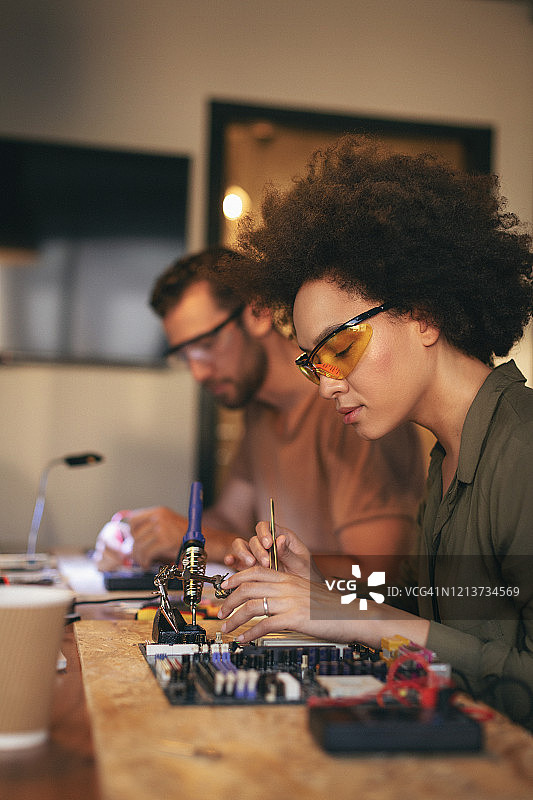 同事们在办公室里加班制作电路板。图片素材