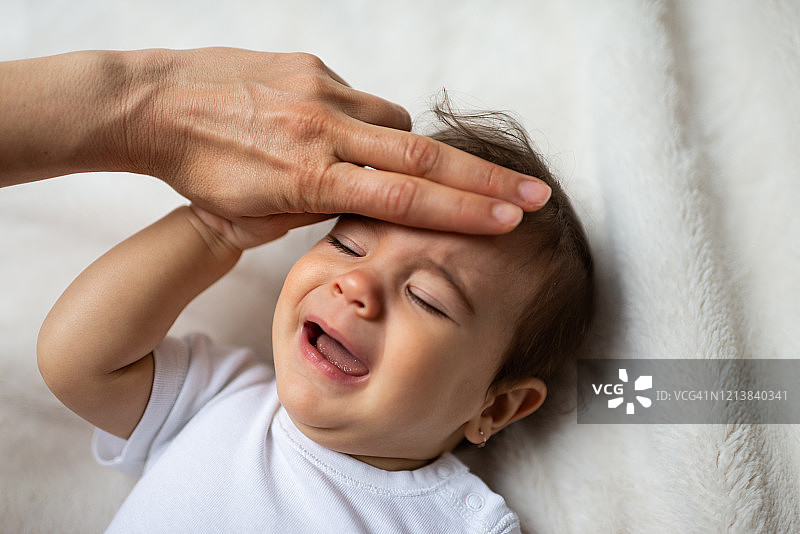 忧心忡忡的母亲在卧室里给婴儿量体温图片素材