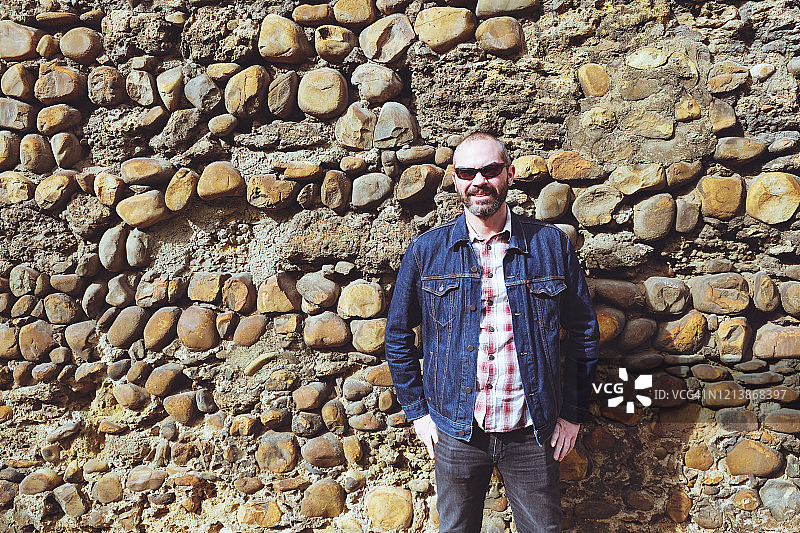 中年男子靠在石墙上图片素材