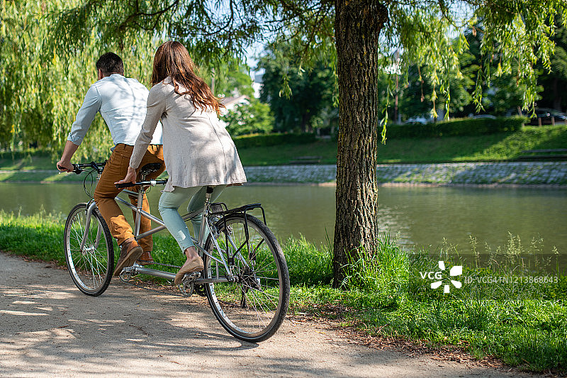 白人夫妇在河岸上骑双人自行车图片素材