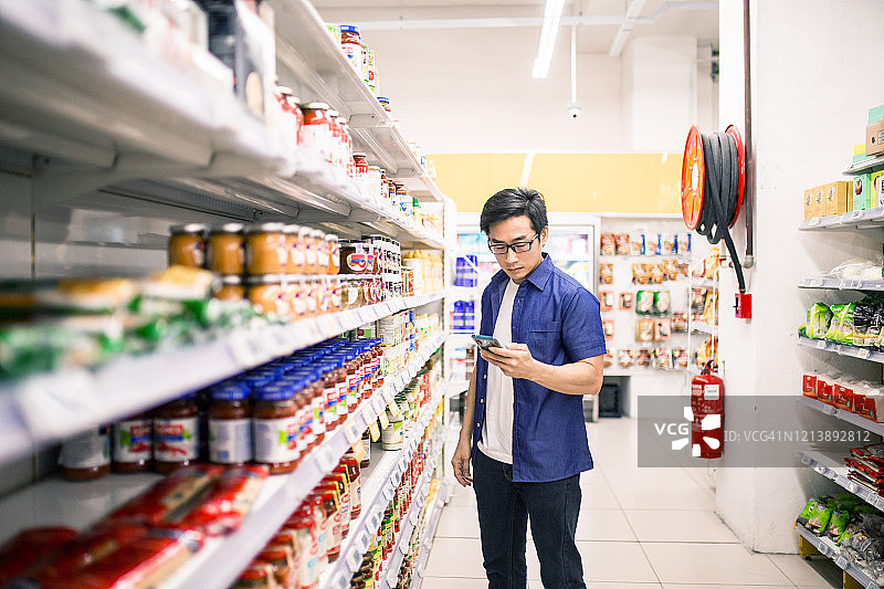 中国男子在超市查看手机购物清单图片素材