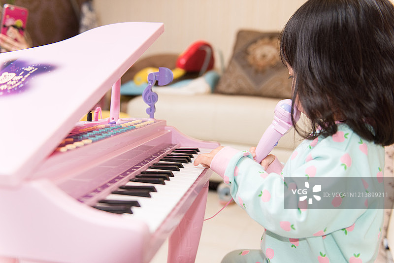 儿童在家快乐地弹奏玩具钢琴唱歌图片素材