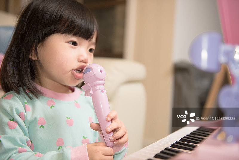 儿童在家快乐地弹奏玩具钢琴唱歌图片素材