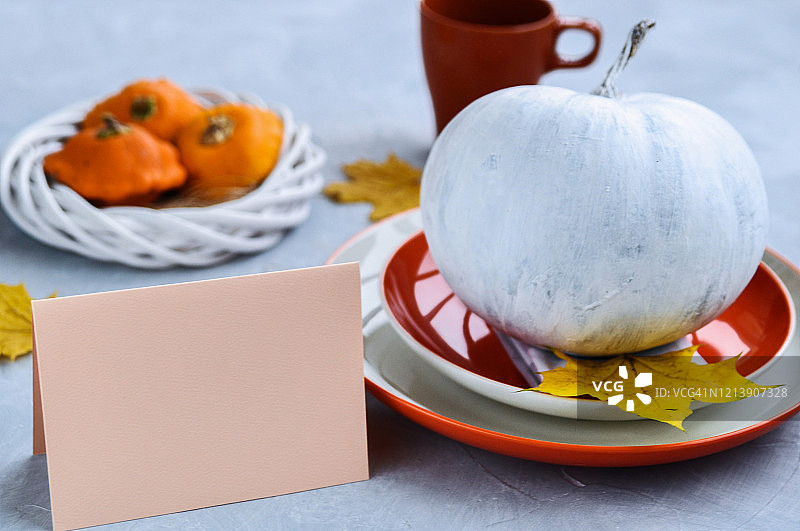 万圣节或感恩节卡片，桌面装饰有白色南瓜、橙色盘子和黄色树叶图片素材
