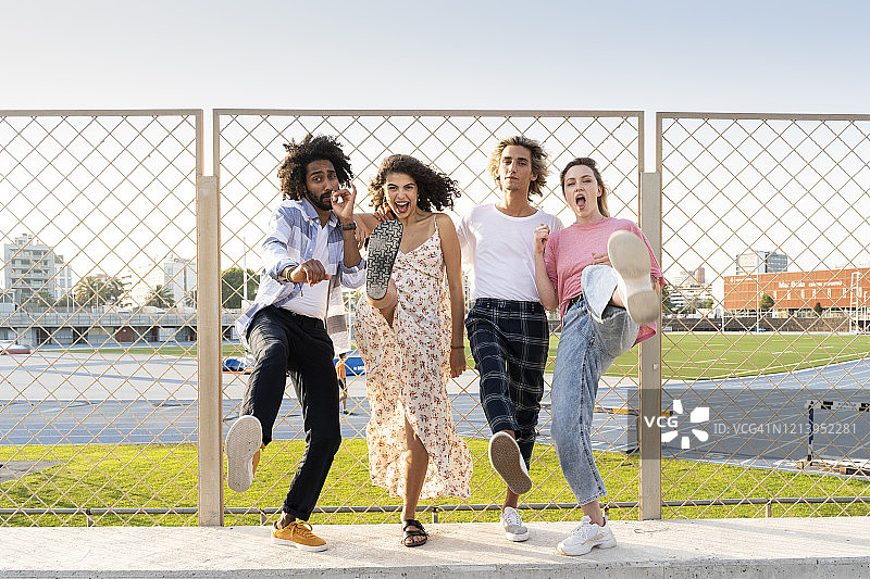 在铁丝网围栏前摆姿势的快乐朋友图片素材