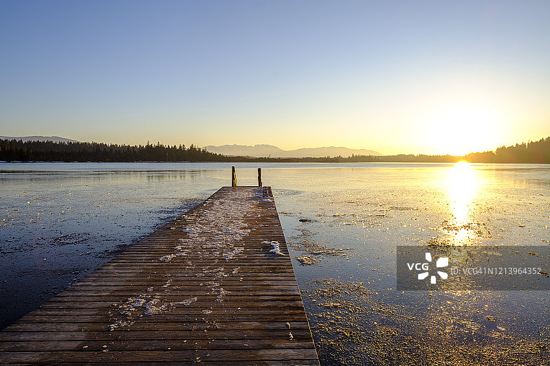 德国巴伐利亚，日落时分冰冻的基希湖和码头图片素材