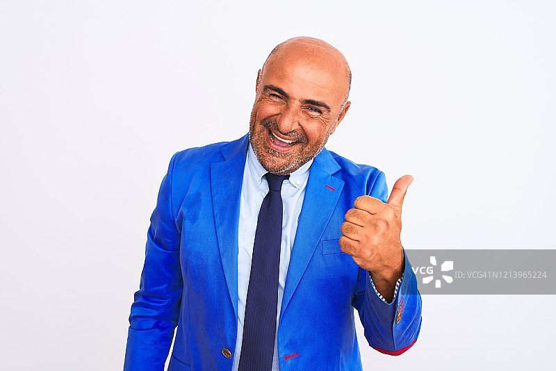 中年商人身穿西装站在白色背景前，高兴地竖起大拇指，面带微笑，表达赞同，展示成功。图片素材