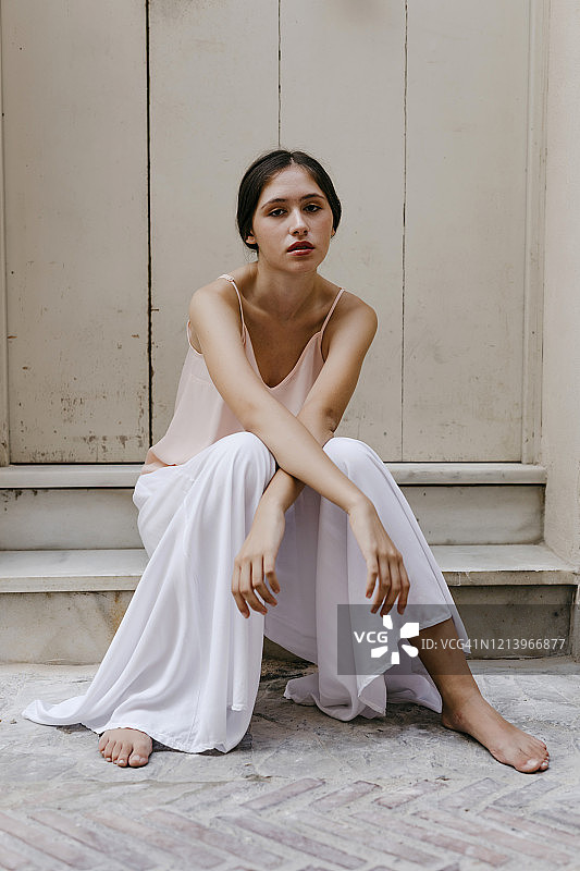 赤脚少女穿着白色裙裤坐在户外台阶上 портрет图片素材