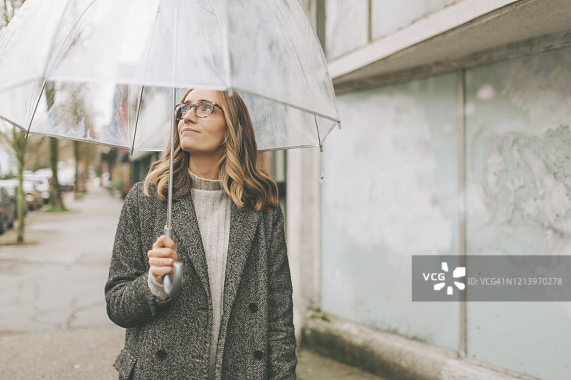 在雨中撑伞行走的金发女人图片素材