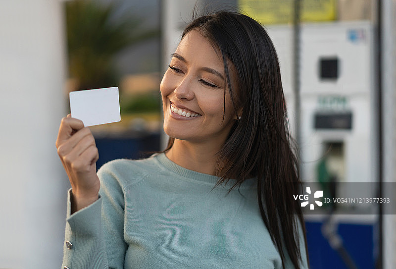 在加油站展示优惠卡的年轻女子图片素材