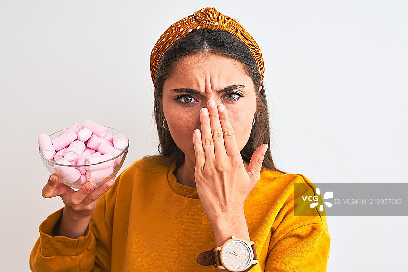 年轻女子手拿棉花糖碗，捂嘴震惊，为失误感到羞愧图片素材
