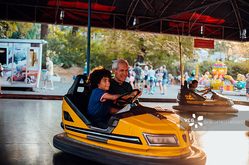 男孩和他的爷爷乘坐碰碰车玩耍图片素材