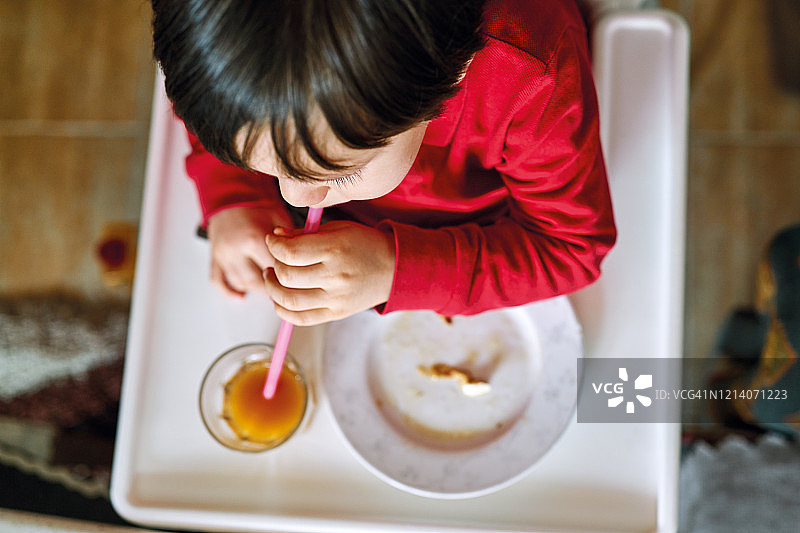 可爱儿童在厨房餐桌旁喝果汁吃蔬菜图片素材