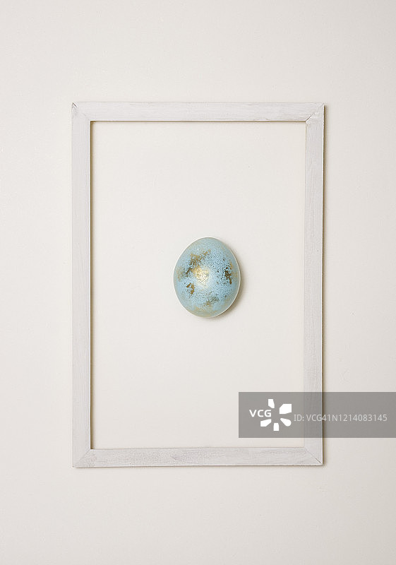 白色背景下的金色蓝色复活节彩蛋和白色木制框架。简约风。复活节快乐！图片素材