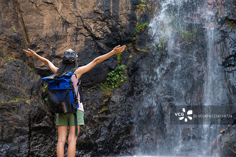 年轻女背包客在泰国北碧府享受雨林瀑布图片素材