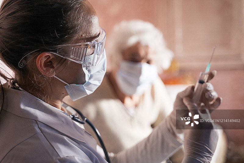 隔离期间的新冠病毒防护：女医生在一位老妇人家中为其接种疫苗图片素材