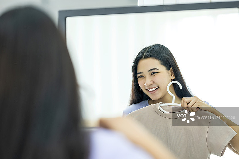 亚洲年轻女子在家中衣橱里挑选休闲装图片素材
