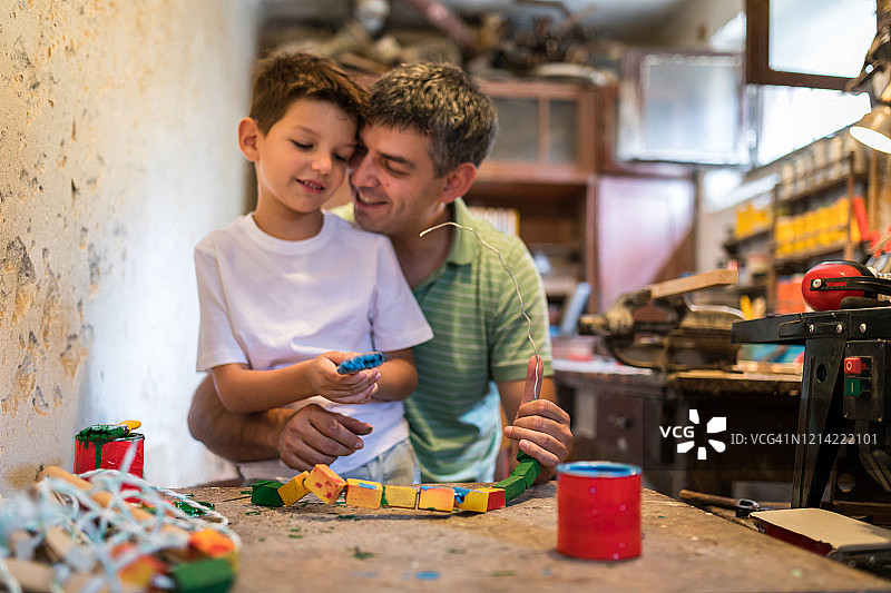 父亲一边绘画一边唱歌，拥抱儿子图片素材