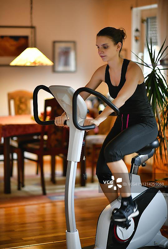 年轻女人在斯图加特的家中在测功仪上做运动（德国巴登-符腾堡州）图片素材