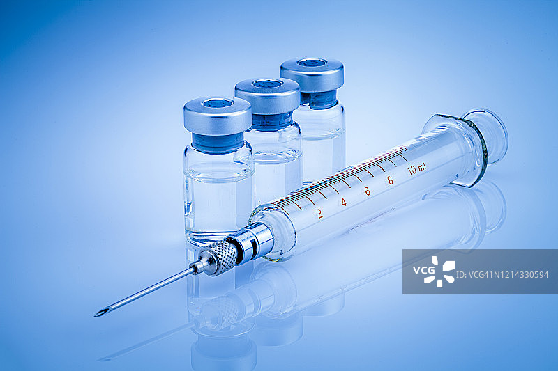 新冠病毒疫苗：蓝色背景上的注射器和药瓶图片素材