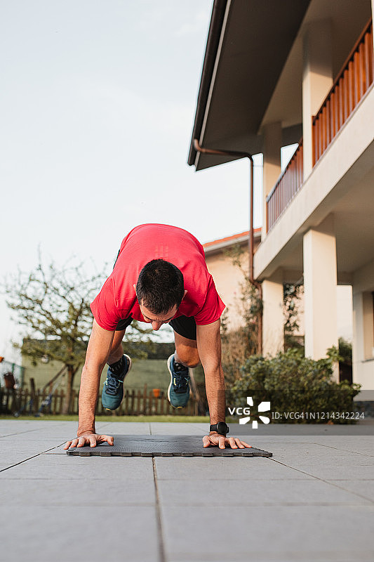 年长的男人在日落时分在家里的露台上做波比跳图片素材