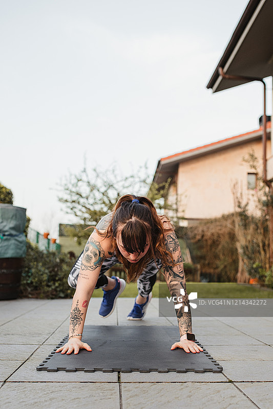 年轻女人在自家露台日落时分做波比跳图片素材