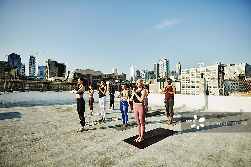 在屋顶俯瞰城市景观的瑜伽课程图片素材