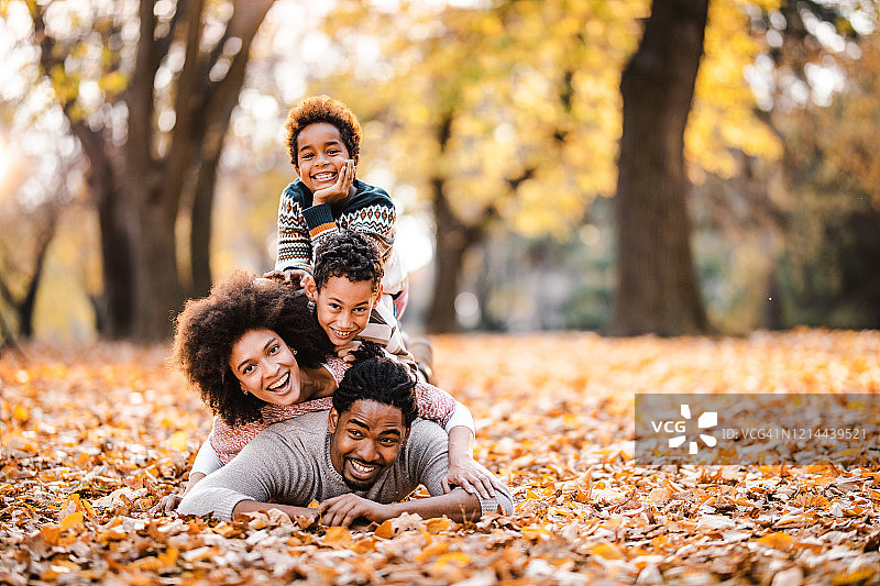 快乐的非洲家庭在秋叶中堆叠人塔图片素材