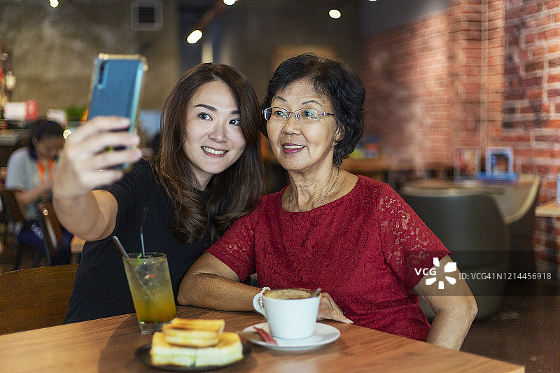 中年妇女在当地咖啡馆与年长的母亲喝咖啡图片素材