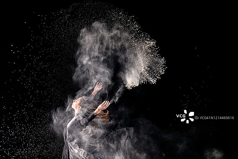 年轻芭蕾舞演员伴着粉尘起舞图片素材
