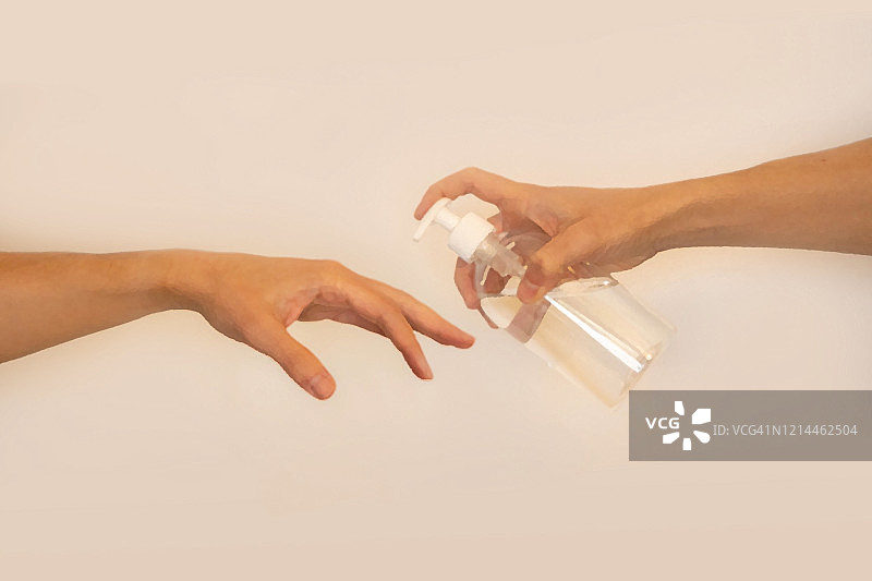 创意图片，像《亚当的创造》绘画一样将凝胶消毒剂涂抹在手上。COVID-19图片素材