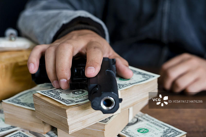 手持枪支，置于一堆金钱之上图片素材