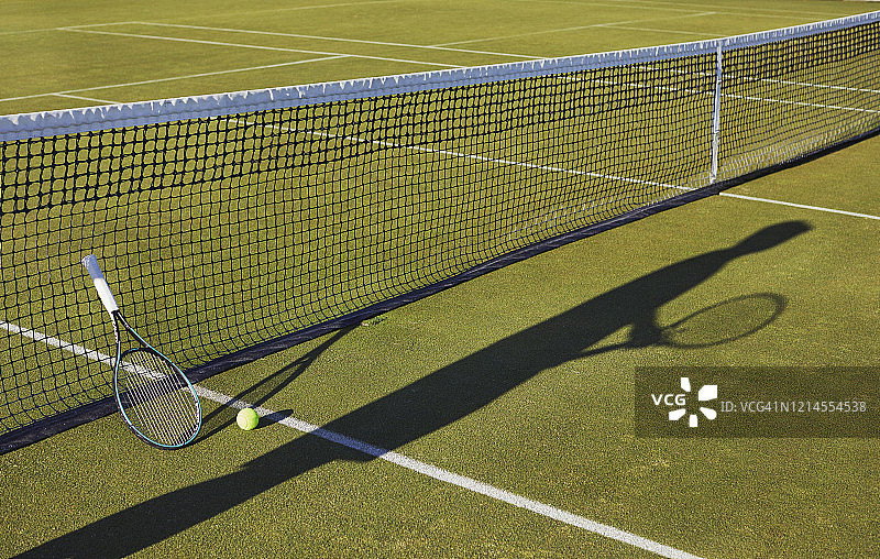 草地网球场上手持网球拍的人的长阴影静物图片素材