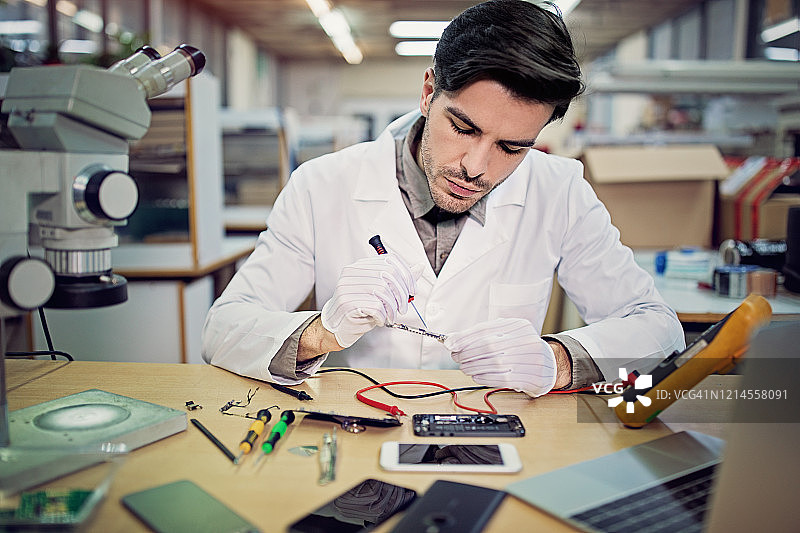 男子在维修店修理手机图片素材