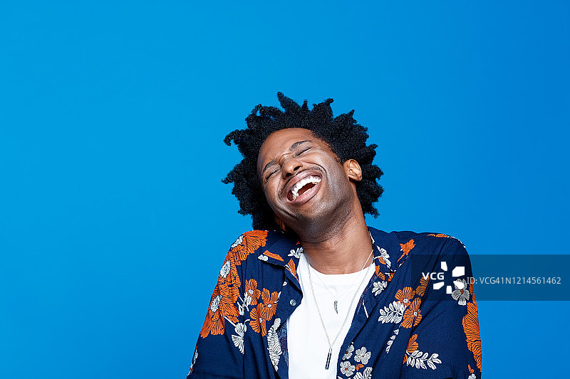 在蓝色背景下的穿着夏威夷衬衫的时髦年轻人图片素材