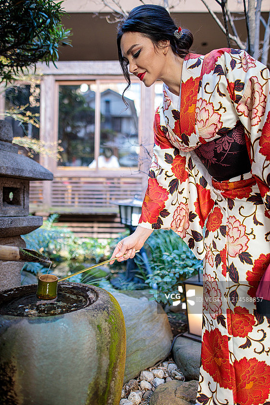 穿着和服在日式庭院汲水的白人女性图片素材