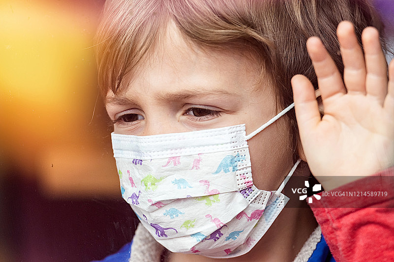 戴着医用口罩看窗外的小男孩图片素材