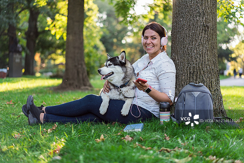 女人和漂亮的哈士奇在公园里放松图片素材